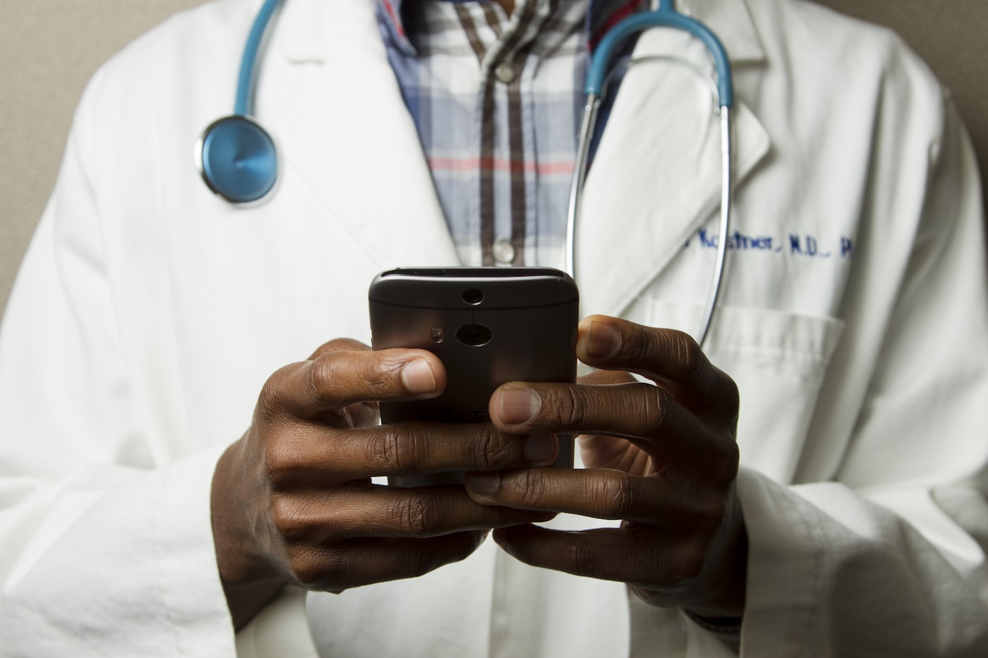 A clinician in a white coat reviewing a patient assessment on a smartphone